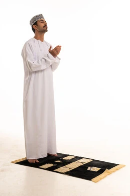 رجل عُماني يصلي على السجادة خلفية بيضاء