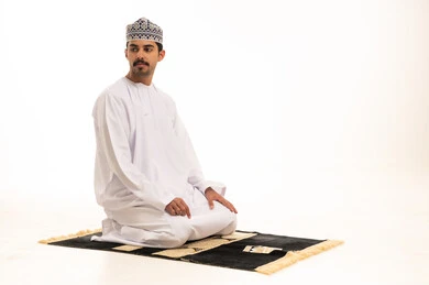 Omani Man Praying on Mat in Traditional Dishdasha