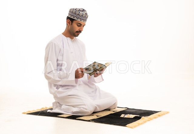 رجل عماني يقرأ القرآن الكريم على سجادة الصلاة