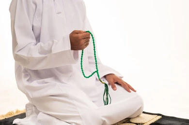 رجل مسلم يمسك مسبحة على سجادة صلاة