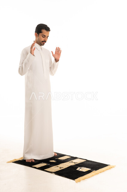 رجل سعودي بالثوب الأبيض يؤدي الصلاة خلفية بيضاء
