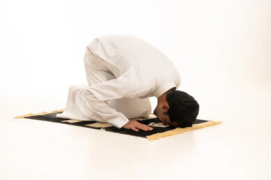 رجل سعودي في وضعية السجود بخلفية بيضاء