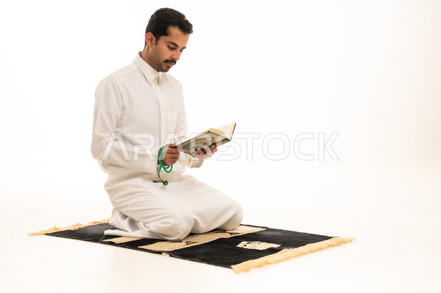رجل سعودي يقرأ القرآن الكريم على سجادة الصلاة