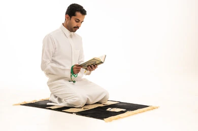 رجل سعودي يقرأ القرآن الكريم على سجادة الصلاة