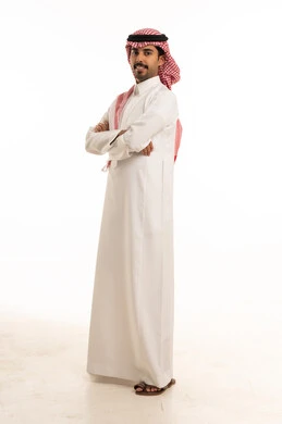 رجل سعودي مبتسم بالثوب الأبيض التقليدي في الاستوديو