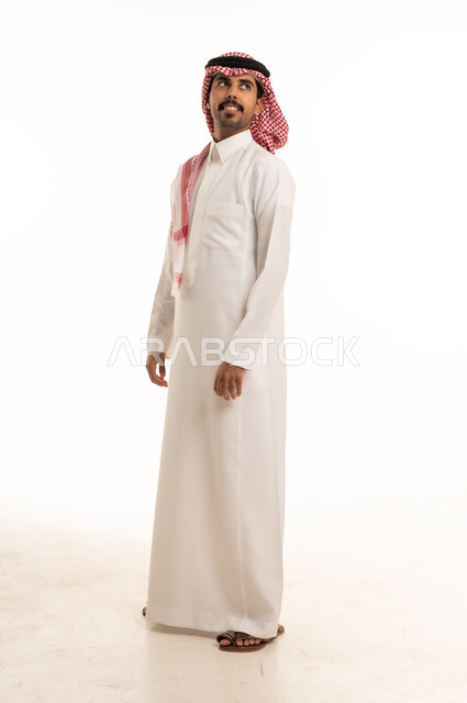 رجل سعودي بالثوب التقليدي ينظر للأعلى في الاستوديو