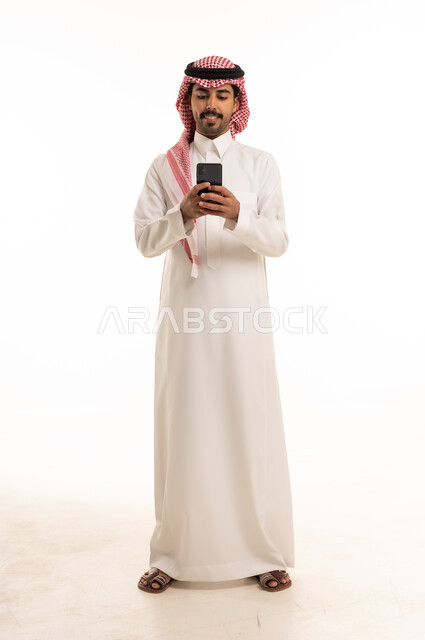 Saudi Man in Traditional Thobe Using Smartphone