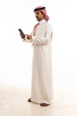 رجل سعودي بالزي التقليدي يستخدم الهاتف الذكي