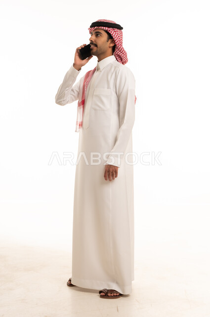 رجل سعودي يتحدث بالهاتف الذكي في استوديو أبيض