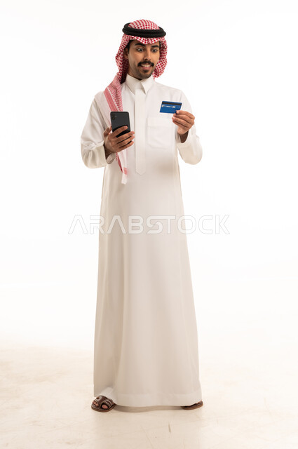 رجل سعودي يحمل هاتف ذكي وبطاقة ائتمان