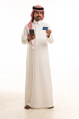رجل سعودي يحمل هاتف ذكي وبطاقة ائتمان
