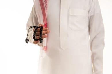 رجل سعودي بالثوب يمسك مسبحة سوداء