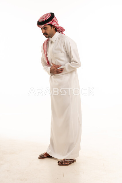 رجل سعودي بالزي التقليدي يعاني من ألم في المعدة