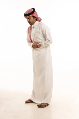 رجل سعودي بالزي التقليدي يعاني من ألم في المعدة