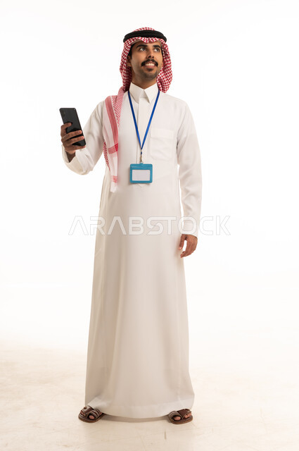 رجل سعودي بالزي التقليدي يمسك هاتفاً ذكياً