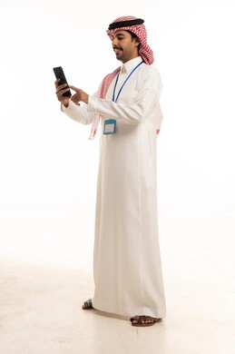 رجل سعودي بالثوب التقليدي يستخدم الهاتف الذكي