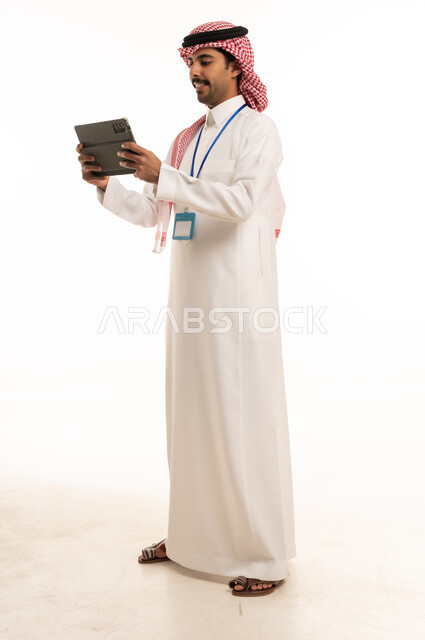 رجل أعمال سعودي يحمل جهاز لوحي بخلفية بيضاء