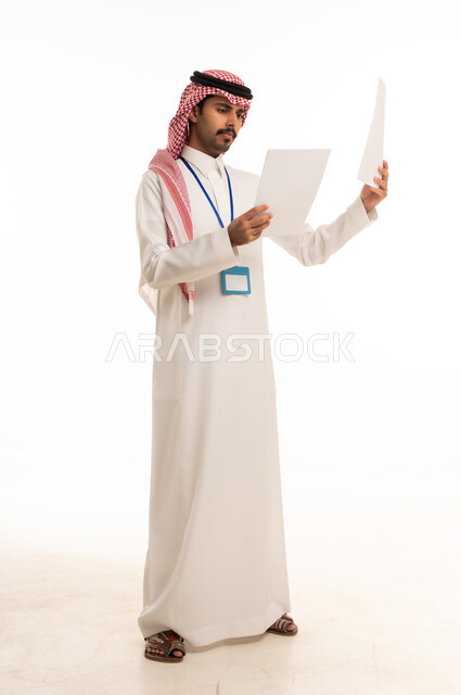 Saudi Man in Traditional Thobe Reviewing Documents