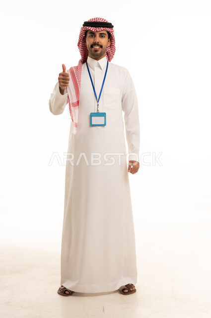 رجل سعودي بالثوب التقليدي يرفع إبهامه على خلفية بيضاء