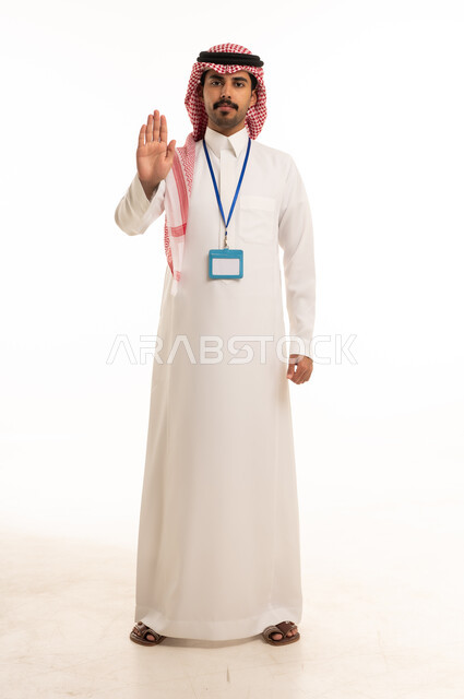 رجل سعودي بالزي التقليدي يقوم بإشارة التوقف