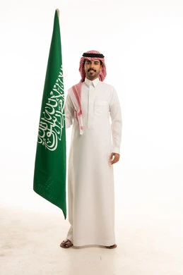 رجل سعودي يمسك العلم الوطني السعودي بخلفية بيضاء