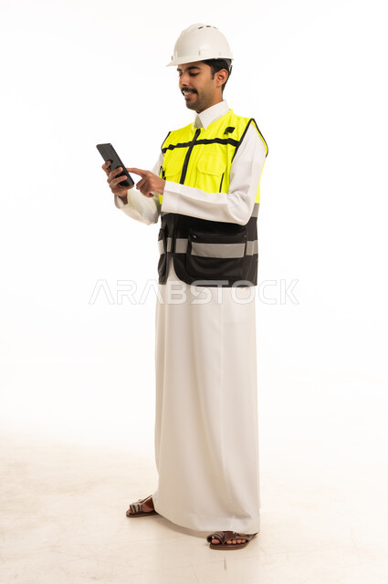 مهندس سعودي يرتدي سترة السلامة ويستخدم الجوال