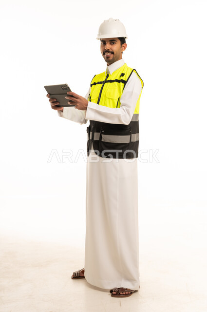 مهندس سعودي بمعدات السلامة يحمل جهازاً لوحياً