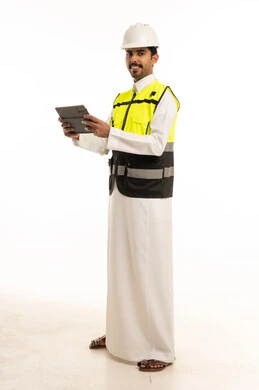 مهندس سعودي بمعدات السلامة يحمل جهازاً لوحياً