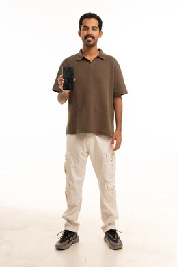 شاب عربي يمسك هاتفاً ذكياً على خلفية بيضاء