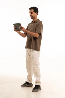 شاب سعودي يستخدم جهاز لوحي أمام خلفية بيضاء