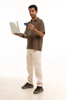 رجل سعودي يستخدم اللابتوب وبطاقة الائتمان للتسوق