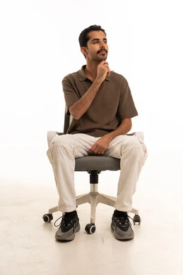 شاب سعودي متأمل يجلس على كرسي مكتب في استوديو