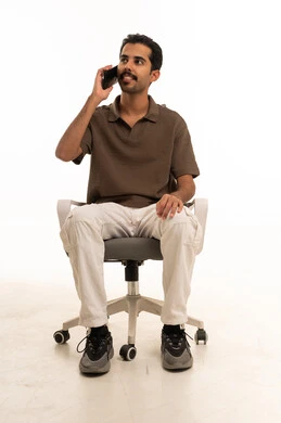 رجل سعودي يتحدث بالجوال جالسا على كرسي مكتب