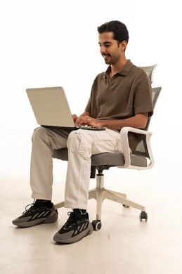 رجل سعودي يستخدم اللابتوب على كرسي مكتب في استوديو