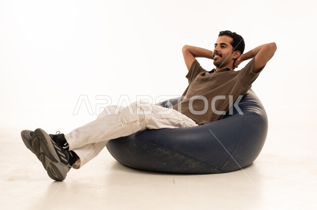 Saudi Man Relaxing on Blue Bean Bag White Background