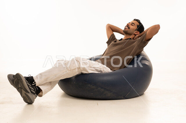 Middle Eastern Man Relaxing on Blue Bean Bag in Studio