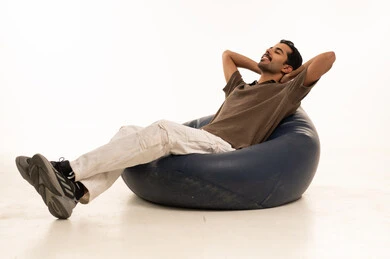شاب عربي يستلقي على مقعد بين باج في استوديو أبيض