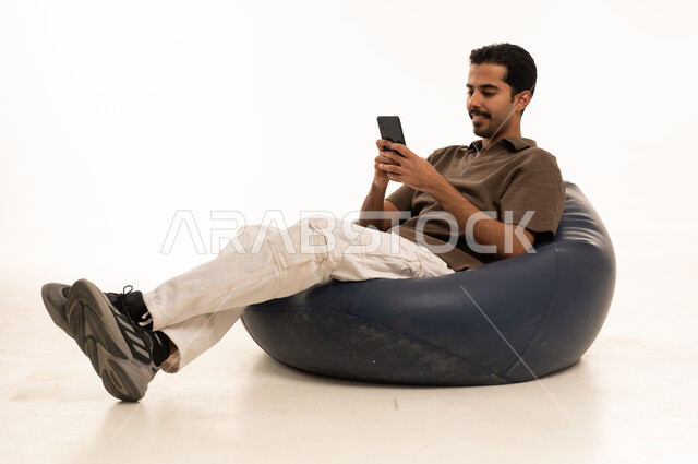 Saudi Man Using Smartphone on Blue Bean Bag Chair