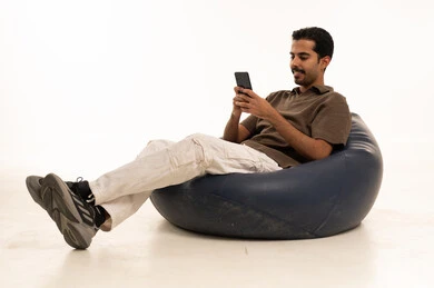 رجل سعودي يستخدم الهاتف الذكي على كرسي بين باج