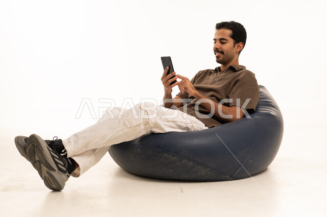 Saudi Man Using Smartphone on Bean Bag Chair