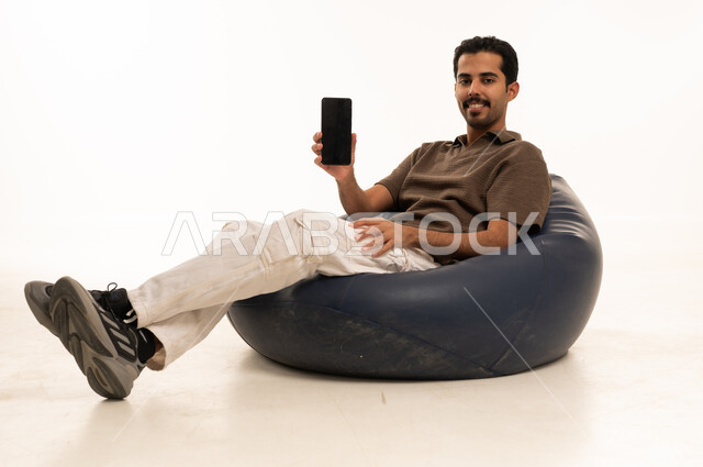 Saudi Man Holding Blank Smartphone on Bean Bag