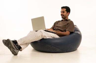 Saudi Man Using Laptop on Beanbag White Background