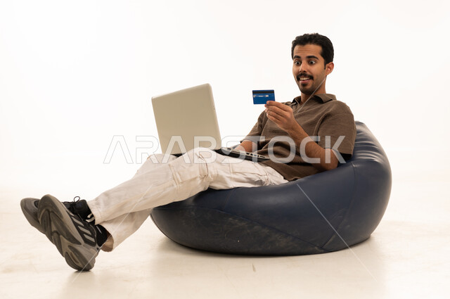 Arab Man Using Laptop and Credit Card on Blue Bean Bag