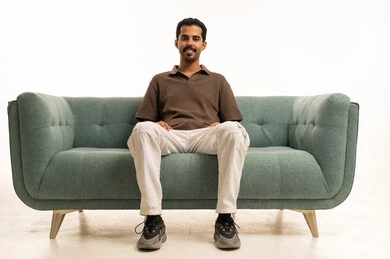 شاب سعودي يجلس على أريكة في خلفية استوديو