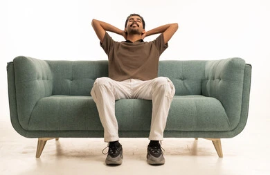 شاب عربي يسترخي على أريكة خضراء في الاستوديو