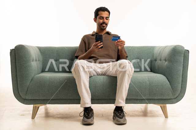 شاب سعودي يستخدم الهاتف وبطاقة الائتمان للتسوق