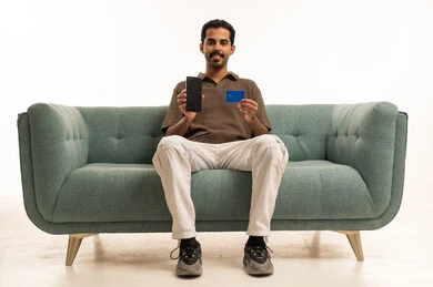 Saudi Man Holding Credit Card and Smartphone on Sofa