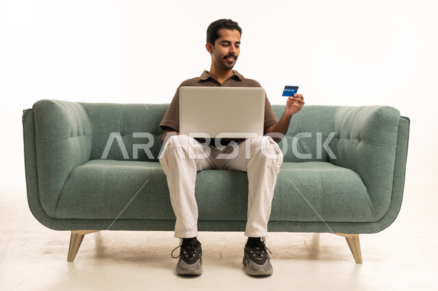 Saudi Man Shopping Online with Laptop on Sofa