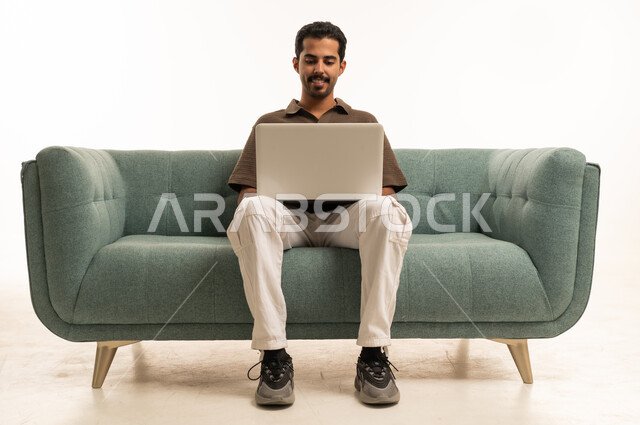 Arab Man Using Laptop on Teal Sofa Studio