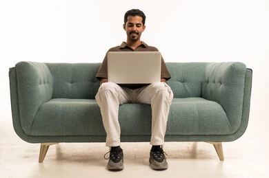 Arab Man Using Laptop on Teal Sofa Studio